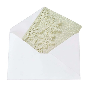 Detailed laser-cut snowflake and pine tree patterns on silver glitter greeting card with envelope