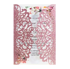 Close-up of laser cut hollow invitation card with pink glitter texture and floral inserts
