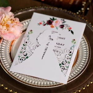 Detail of laser-cut wedding invitation featuring a floral inner card on a decorative plate
