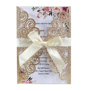 Détail de la pochette dorée découpée au laser avec ruban crème et carte de mariage fleurie