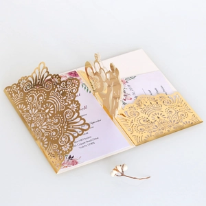 Detail of 3D laser-cut gold wedding invitation with floral patterns and pop-up couple