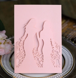 Detail of laser-cut pink wedding invitation showing two brides and floral patterns