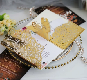 Detail der lasertgeschnittenen Gold-Hochzeitseinladung mit 3D-Popup-Paar und weißer Karte