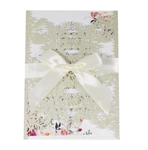 Macro detail of laser-cut snowflake wedding invitation with glitter and satin bow