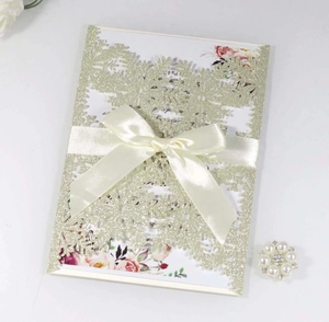 Detail of glitter gold laser-cut wedding invitation with silk bow and floral insert
