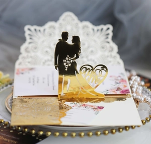 Detail einer lasergeschnittenen Hochzeitseinladung mit goldenen 3D-Brautpaar-Silhouetten