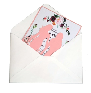 Detail of laser-cut wedding invitation featuring pink silhouette and floral inner card
