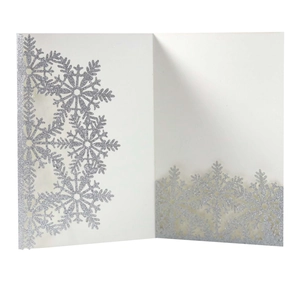 Detail view of laser-cut silver glitter snowflake patterns on elegant white holiday card