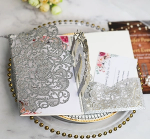 Close-up of laser-cut silver glitter wedding invitation set with intricate patterns
