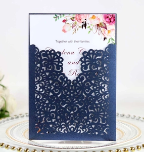 Detail of laser-cut navy blue wedding invitation with elegant floral texture and gold accents