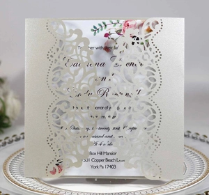 Detail of square laser-cut wedding invitation with elegant floral filigree on pearlescent paper