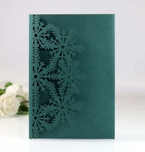 Detailed laser-cut snowflake patterns on dark green cardstock for festive invitations