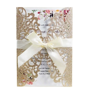 Intricate laser-cut blue glitter wedding invitation featuring elegant silk bow detail