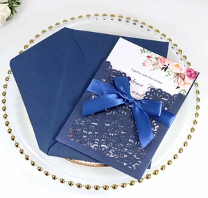 Detailed laser-cut pattern on navy blue wedding invitation with ribbon and floral insert