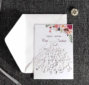 Close-up of laser-cut wedding invitation with white dress design and floral details