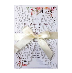 Detail of laser-cut wedding invitation with beige satin ribbon and floral printed insert
