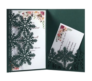 Detail of laser-cut snowflake patterns on dark green invitation card with RSVP card set