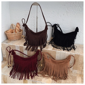 Detail of bohemian suede bucket bags with long tassels and wooden bead strap accents