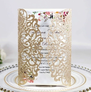 Macro view of laser-cut gold glitter invitation with elegant floral print inner card