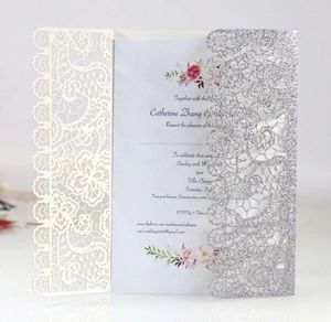 Detail of laser-cut lace wedding invitation with silver glitter and floral print card