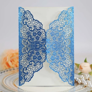 Intricate laser-cut blue glitter wedding invitation with elegant lace pattern and insert