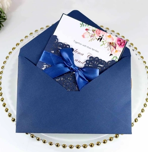 Detail of laser-cut navy blue wedding invitation with satin bow and floral inner card