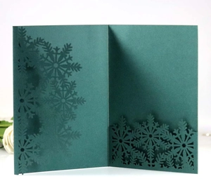 Close-up of laser-cut snowflake patterns on dark green holiday greeting cards