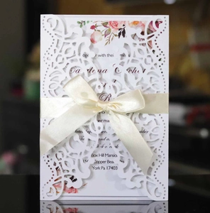 Detail of laser-cut wedding invitation featuring floral inner card and cream satin bow