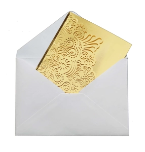 Detail of laser-cut gold wedding invitation featuring intricate floral patterns and white envelope