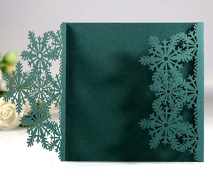 Intricate laser-cut snowflake details on dark green cardstock for festive invitations