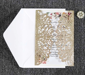 Detail of glitter laser cut wedding invitation with floral insert and white envelope