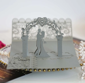 Detailed laser-cut 3D pop-up wedding card showing a couple under a heart floral archway