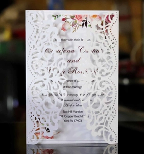 Detail of laser-cut wedding invitation with white intricate cover and floral inner card