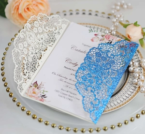 Detail of laser cut wedding invitations with glitter covers and floral cards in elegant tray