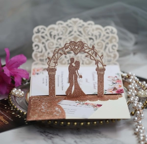 Close-up of 3D rose gold glitter laser cut wedding invitation with romantic couple silhouette