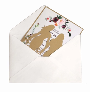 Detail of laser-cut gold wedding invitation featuring elegant silhouette and floral inner card