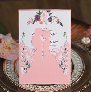 Detailed laser-cut pink wedding invitation with romantic couple silhouette and flowers