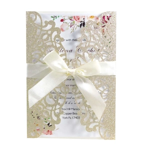 Macro detail of royal blue laser cut invitation with gold glitter and white silk ribbon