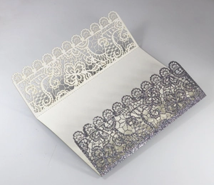 Close-up of laser-cut lace invitation with silver glitter detail and white cardstock