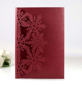 Macro shot of laser-cut snowflake hollow pattern on burgundy pearlescent greeting card