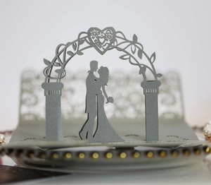 Close-up of laser cut 3D wedding card with romantic couple under a floral arch