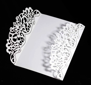 Detailed view of intricate laser-cut floral pattern on a white wedding invitation card