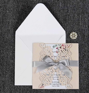 Detail of laser-cut floral wedding invitation with grey ribbon and elegant inner page