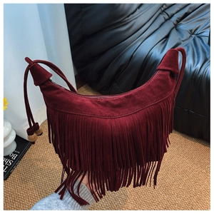Détail d'un sac seau bordeaux en daim avec franges et perles en bois sur la bandoulière