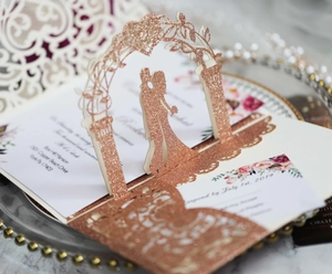 Macro view of rose gold glitter 3D pop-up wedding card with laser-cut kissing couple