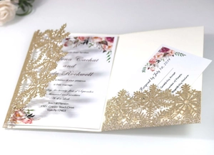 Macro detail of laser-cut snowflake design on gold glitter paper wedding invitation