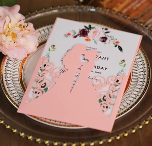 Laser-cut pink invitation cover with couple silhouette on a decorative dinner plate