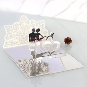 Macro view of laser-cut 3D wedding card with silver bride and groom silhouettes