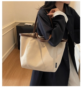 Detail of canvas tote bag showing beige fabric texture and brown leather trim accents