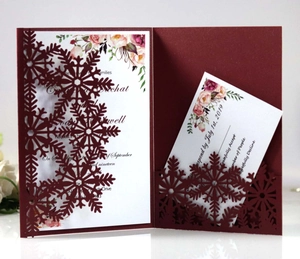 Detailed laser-cut burgundy invitation card set featuring intricate snowflake patterns
